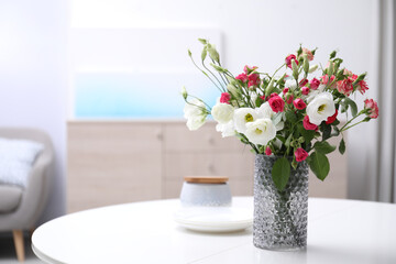 Vase with beautiful flowers on white table in room, space for text