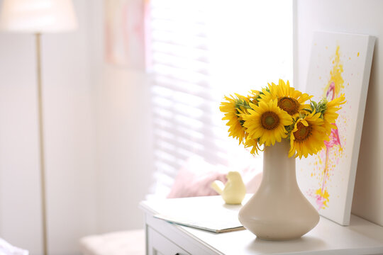 Beautiful bouquet of sunflowers in vase on white table indoors. Space for text