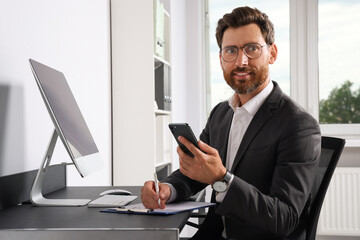 Handsome businessman using smartphone at workplace in office