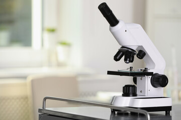 Modern medical microscope on metal table in laboratory, space for text