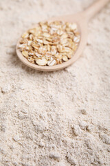 Spoon with oat flakes on flour, closeup
