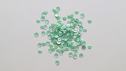 Pile of green sequins on light grey background, flat lay