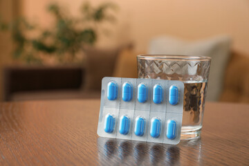 Glass of water and pills on wooden table indoors, space for text. Potency problem concept