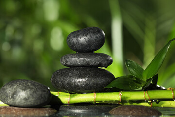 Wet stacked stones on bamboo stems against blurred background, closeup