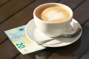 Tasty hot coffee and payment for order on table, closeup. Leave tip