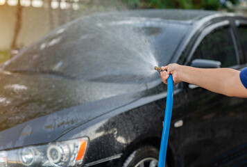 The man use pressor spray water car wash at home.