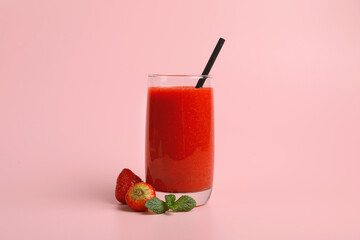 Glass with delicious berry smoothie and fresh strawberries on pink background