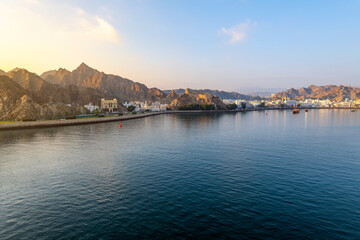 Fototapeta na wymiar Early morning view from the sea of the old city, Mutrah Fort and Mutrah Corniche waterfront at the Port Sultan Qaboos of Muscat Oman along the Gulf of Oman in the Arabian Sea 