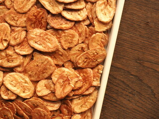 Top view banana chips on wooden background