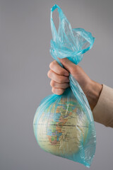 A woman is holding a globe in a plastic bag on a white background. 