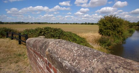 Wide Shot of British countryside with Aston Lock looking down on to Trent and Mersey Canal with stone bridge walls in foreground