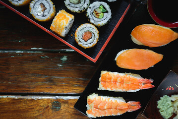 Sushi Set nigiri shrimp and salmon and sushi california rolls with avocado and maki with carrot, on wood,top view