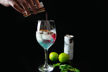bartender making cocktail with ice and citrus fruits lime in glass on black background