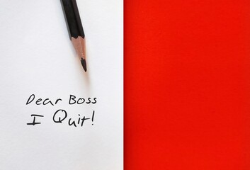 Pencil on white paper with handwritten text DEAR BOSS I QUIT, on red copy space background, concept...