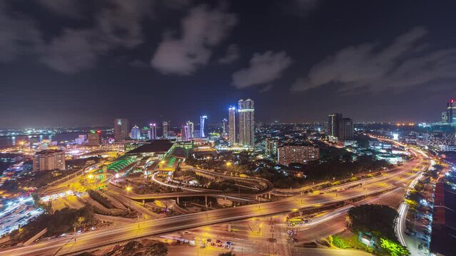 Aerial time lapse of Johor Bahru city with tall buildings from afar in clear sky at night and busy traffic on elevated highway. Tilt up motion timelapse. Prores 4KUHD