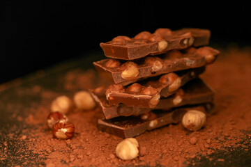 Chocolate pieces with nuts close-up on a black background.Milk chocolate. 