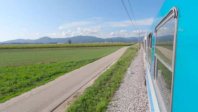 Passenger train in Slovenia leaving Ljubljana among fields, onboard camera