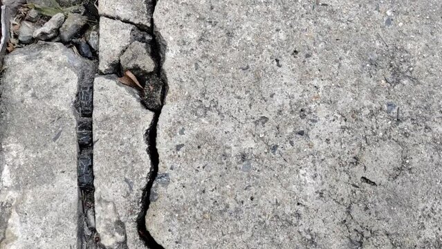 Cracked concrete ground broken at floor or street road from bad construction or earthquake