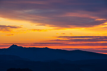 鮮やかなオレンジ色の黄昏の空と山のシルエット。
