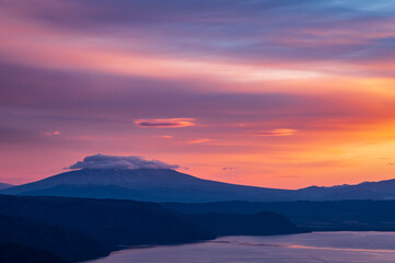 鮮やかなオレンジ色の黄昏の空と山のシルエット。