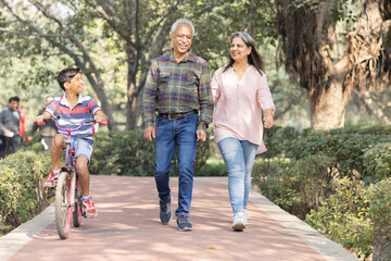 Obraz premium Happy grandparents spending leisure time with grandson at park