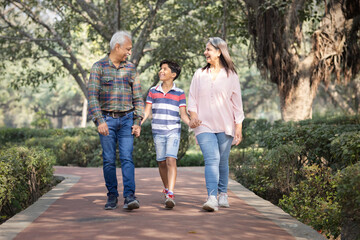 Obraz premium Happy grandparents spending leisure time with grandson at park