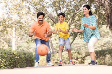 Cheerful family having fun playing with basketball at park.