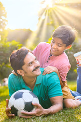 Father and son having fun while playing with football at park.