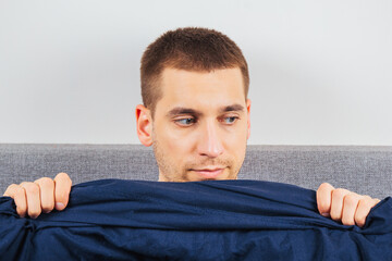 Look to the right. A handsome young guy hiding behind a blanket looks to the side. Direction of...