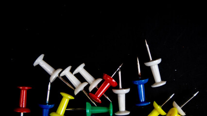 multicolored thumbtacks on a black background