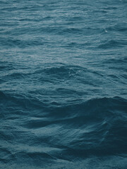 Dark blue-green color of water surface with waves in middle of endless deep sea. Endless wavy expanse of blue sea water. Dark blue waves in deep ocean. Raging aquamarine waves on surface of the water.