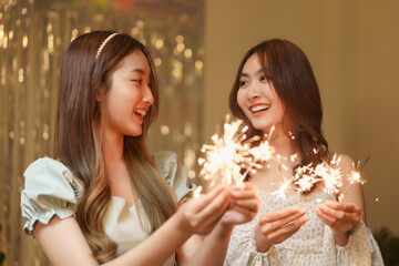 New Year party concept, Two beautiful women holding firework sparklers to celebrating in party
