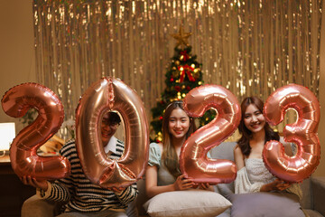 New Year celebration concept, Group of friends holds balloon air pink gold number 2023 in new year party