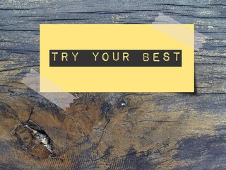Yellow note with motivation message TRY YOUR BEST on wood background, encouraging self reminder to...