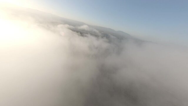 Fast dreamlike speeding FPV drone flying above clouds across Alella woodland terrain, Catalonia