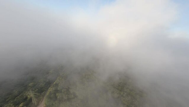 Fast speeding FPV drone flying through clouds and low above Alella woodland valley trees, Catalonia