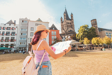 Happy tourist girl with maps, navigating and geolocating on the streets of an old European city of Koln