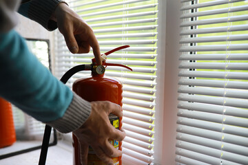 hand presses the trigger fire extinguisher available in fire emergencies conflagration damage...