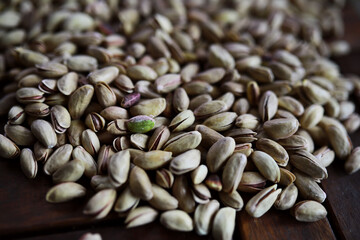 Pistachio nut in sack bag with mint green leaf on wooden table background.