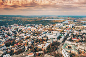 Fototapeta na wymiar Aerial view of Homiel cityscape skyline in autumn sunny day. Bird's-eye view of Gomel TV tower, circus building, residential district and river in autumn sunny day. Dramatic sky over residential