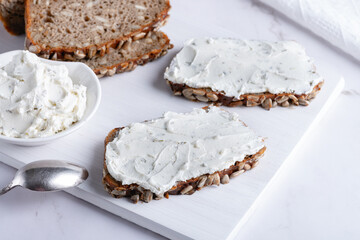 Home made rye bread on a wooden cutting board with curd cheese and ricotta