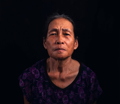 Portrait of an Asian elderly woman wearing short sleeves on a black background.