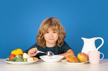 Child eating soup. Children eat breakfast. Studio portrait of small boy child eating soup meal or...