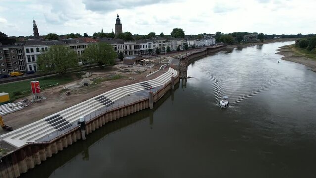 Forward aerial movement showing the quay under construction at river IJssel with work in progress on the IJsselkade boulevard of tower town Zutphen urban development