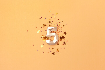 Gold colored number 5 and stars confetti. Festive monochrome concept.