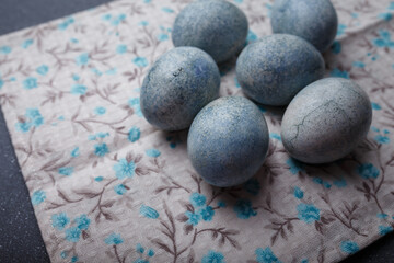 Easter eggs DIY painted blue on grey wooden background with kitchen towel. Close up shot. Happy Easter concept