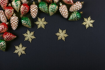 Christmas decorations in the form of golden, red, green cones and snowflakes on a black background with a place for text. Top view.