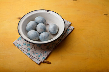 Blue Easter eggs in white bowl on bright yellow background. Easter in Ukraine 2022. Ukrainian national flag colors. Copy space.