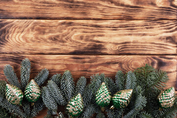 Green branches of a Christmas tree with decorations in the form of green cones on a wooden...