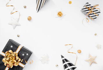 Christmas background. Gifts, party hats, black and golden decorations on white background. Flat lay, copy space